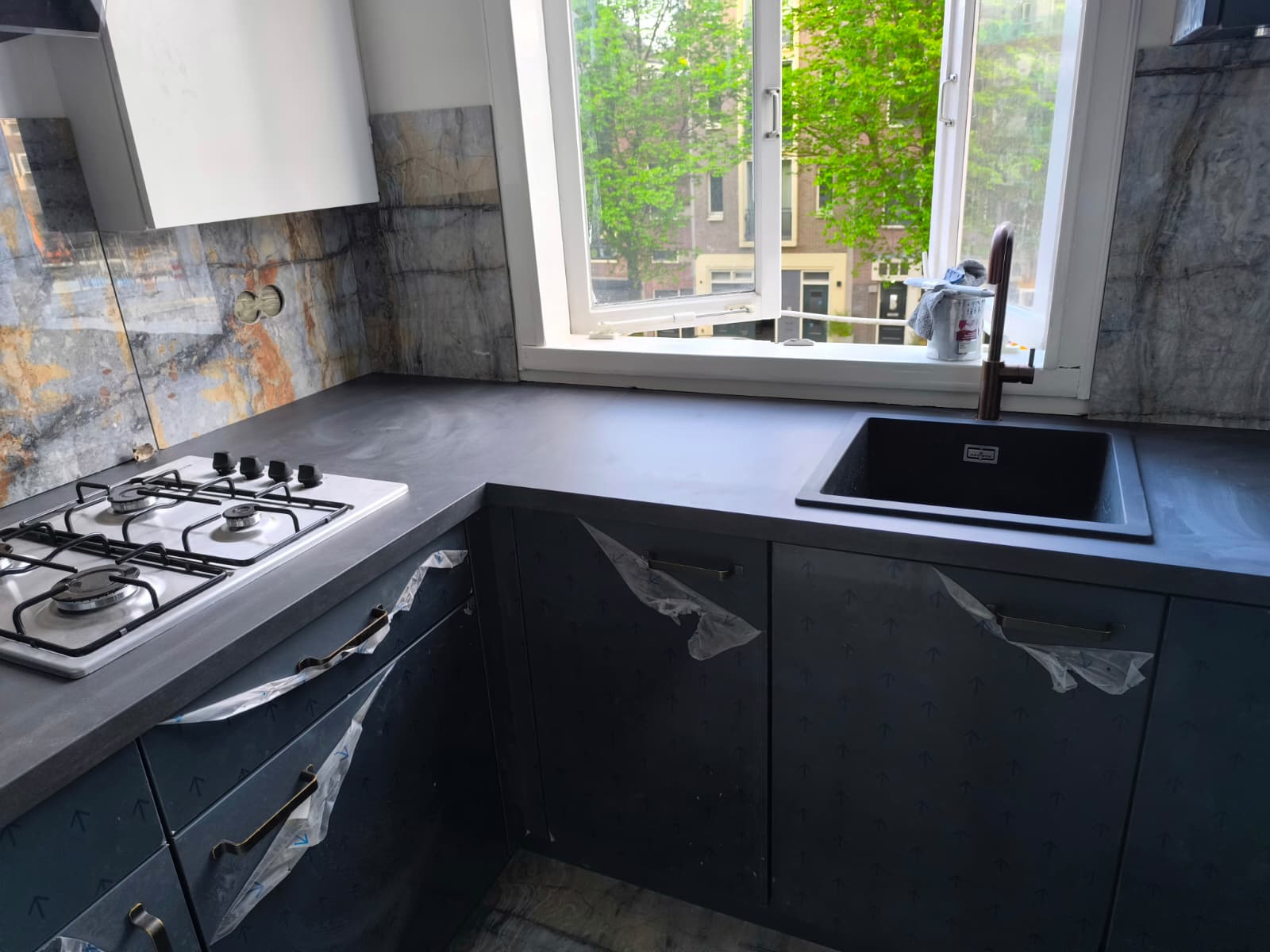 Donkere keuken met marmer-look achterwand door Klusbedrijf 360